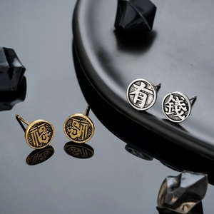 Macro shot of retro matte metal stud earrings with Chinese Fu character and Lucky script
