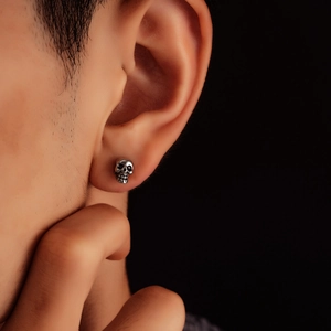 Close-up of vintage silver skull stud earrings with oxidized finish on ear lobe