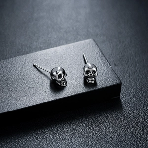 Polished silver skull stud earrings in punk gothic style with detailed metallic engraving