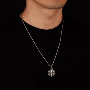 Gros plan d'un collier pendentif boussole argenté vintage pour homme sur fond noir
