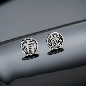 Macro detail of vintage matte silver studs with Fu characters on a reflective surface