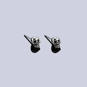 Vintage gothic skull stud earrings in oxidized silver finish with reflective shadows