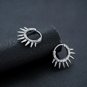 Makro-Detail von Punk-Ohrringen in Retro-Silber mit gehämmerter Metalltextur und Spikes