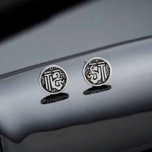Macro shot of vintage matte silver round studs with intricate character engravings