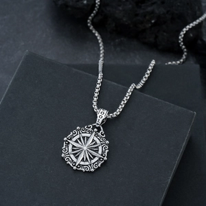 Détail du pendentif boussole vintage avec gravures ciselées sur un fond de pierre noire