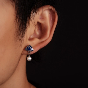 Close-up of blue enamel lotus stud earring with pearl pendant on model ear