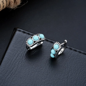 Macro detail of silver hoop earrings with three turquoise beads and bohemian engraving
