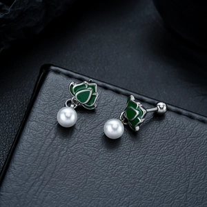 Detail of vintage lotus stud earrings featuring green petals and white pearl drops
