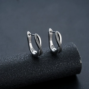 Close-up of silver hoop earrings featuring intertwined smooth and beaded twisted wire