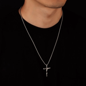 Close-up of silver cross pendant with twisted metal design on circular link chain
