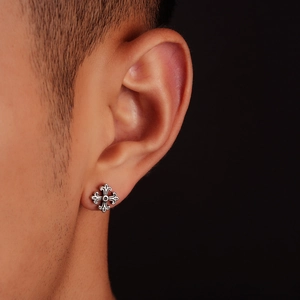 Gros plan sur un clou d'oreille croix gothique vintage avec finition oxydée sur l'oreille