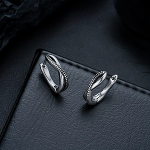 Detailed view of silver twist hoop earrings with bead texture on black leather surface
