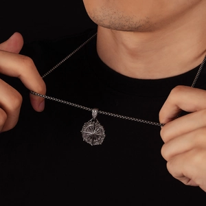 Pendentif boussole vintage avec gravure d'étoile et chaîne maille sur un t-shirt noir