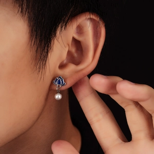 Detailed close-up of lotus stud earring with blue enamel and round white pearl on model