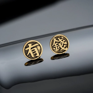 Vintage matte gold studs with relief Chinese characters for wealth on dark reflective surface