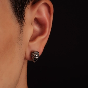 Retro skull stud earring in vintage silver finish shown on ear with a black background