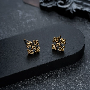 Détail de boucles d'oreilles vintage en or avec croix et pierres noires sur présentoir