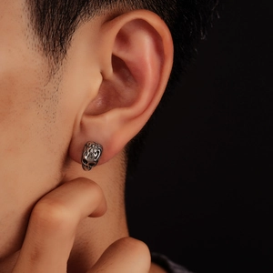 Vintage silver skull stud earring with gothic carved texture shown on a male model