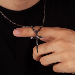 Detail view of a black geometric faceted cross pendant with industrial bead chain