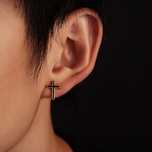 Minimalist gold and black cross stud earring shown on male model with dark background