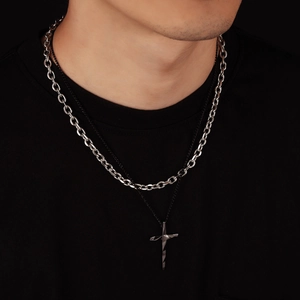 Close-up of double-layered cross necklace with silver links and black chain detail
