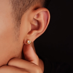 Macro view of gold stud earring with round clear stone on earlobe