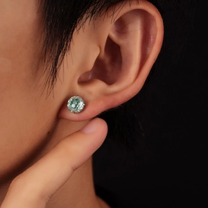 Minimalist four-prong silver stud earring with a mint green gemstone on female model