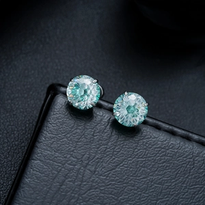 Macro shot of mint green gemstone earrings with four-prong silver settings on black leather