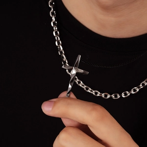 Detail of layered cross pendant with polished faceted edges and heavy silver chain