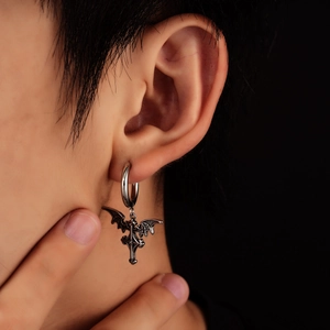 Close-up of gothic silver angel wing and cross charm hoop earring worn on ear