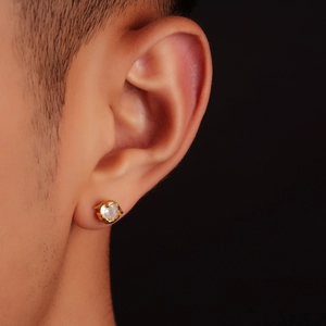 Macro view of gold stud earring with large brilliant-cut clear stone on earlobe