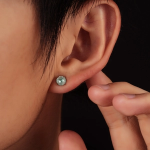 Four-prong mint green gemstone stud earring in stainless steel worn on earlobe