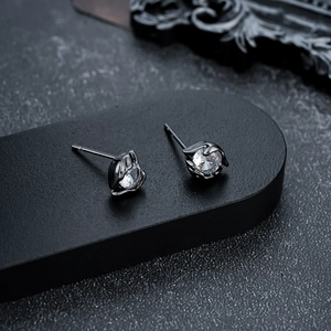 Macro detail of dark-toned stud earrings with clear round cubic zirconia and claw setting