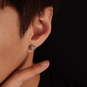 Close-up of silver rose stud earring with a sparkling center crystal on earlobe