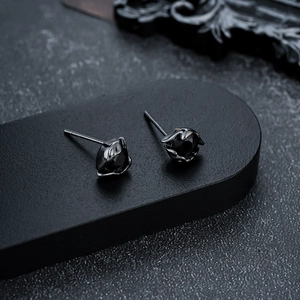 Close-up of black metal eye-shaped stud earrings featuring a faceted black gemstone center