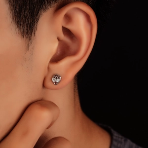 Boucles d'oreilles tête de mort en argent avec yeux en cristal portées sur fond noir pur