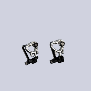 Détail des boucles d'oreilles cœur gothique ajouré avec zircon noir et goutte de métal fluide
