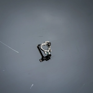 Détail d'une boucle d'oreille cœur fluide argenté avec zircon noir et design gothique