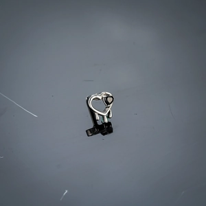 Détail macro d'une boucle d'oreille cœur liquide avec un cristal noir serti