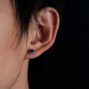 Macro shot of purple cubic zirconia stud earring with four-prong setting on an ear