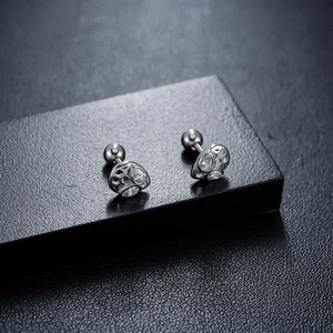 Vue macro de boucles d'oreilles masque en argent avec design ajouré et zircons
