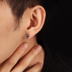 Vue macro d'une boucle d'oreille cœur ajourée avec pierre noire sur le modèle