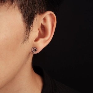 Détail d'une boucle d'oreille cœur en argent avec pierre noire et pendentifs punk