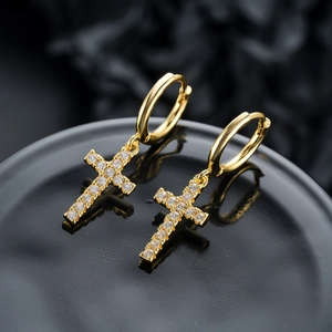 Gros plan de boucles d'oreilles créoles croix plaquées or serties de zircones cubiques