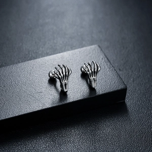 Macro shot of silver gothic skull hand earrings with detailed bone joints and ball back closure