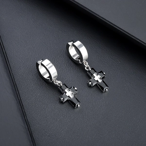 Détail macro de boucles d'oreilles en acier titane avec pendentifs croix en zircon noir