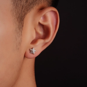 Minimalist silver star stud earring with pavé zircon stones worn on person ear close-up
