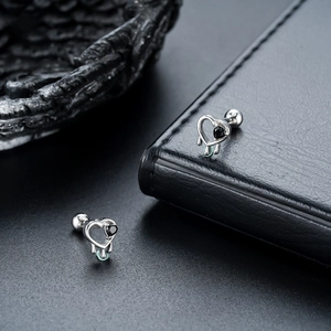 Détail de boucles d'oreilles cœur en argent avec pierre noire et motif de pampille fondue