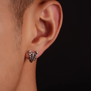Close-up of realistic silver scorpion stud earring on male model in punk style