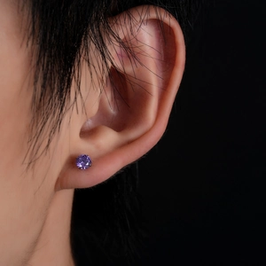 Close-up of a purple round-cut zirconia stud earring with four-prong silver setting
